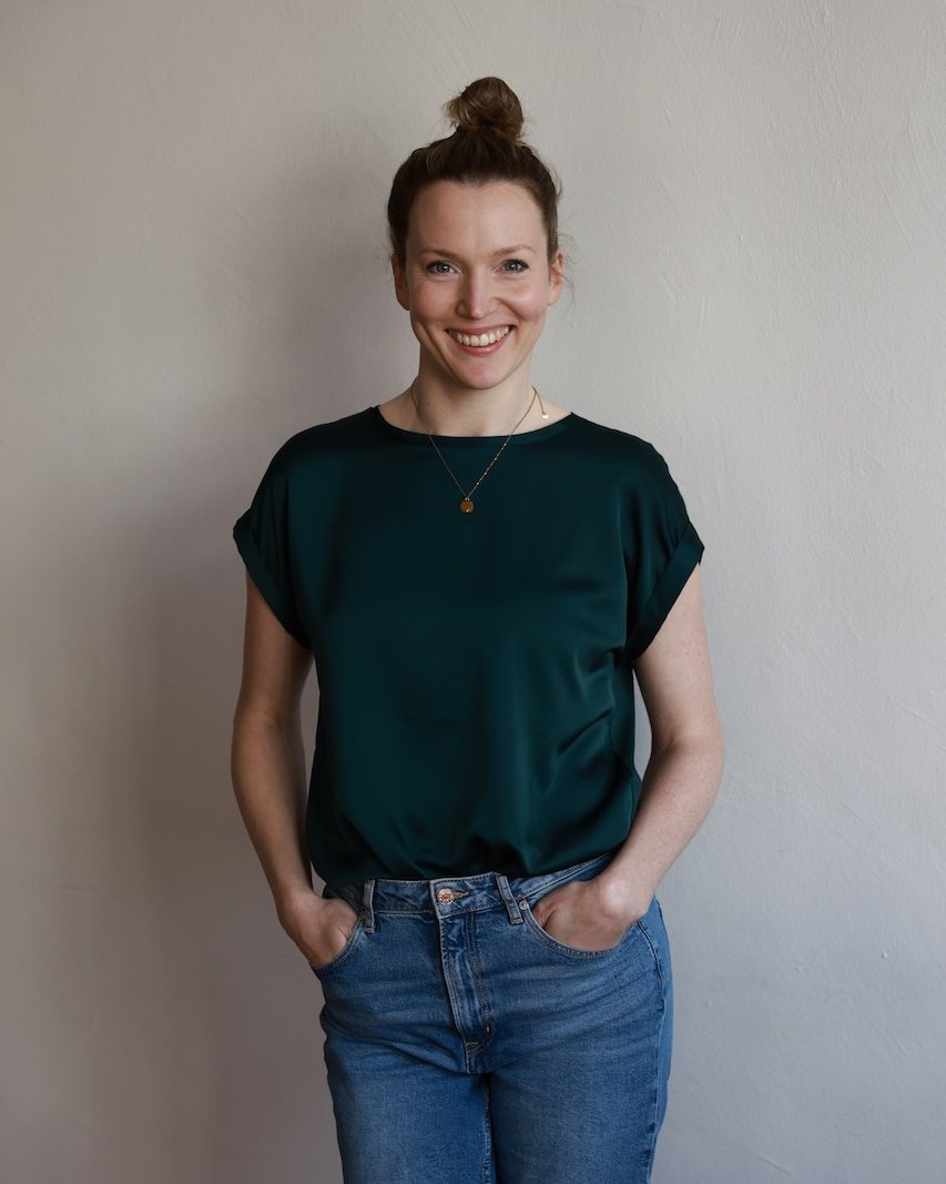 Katharina Schett, Familienaufstellung und Systemaufstellung in Oldenburg und online, lächelnd vor einer hellen Wand